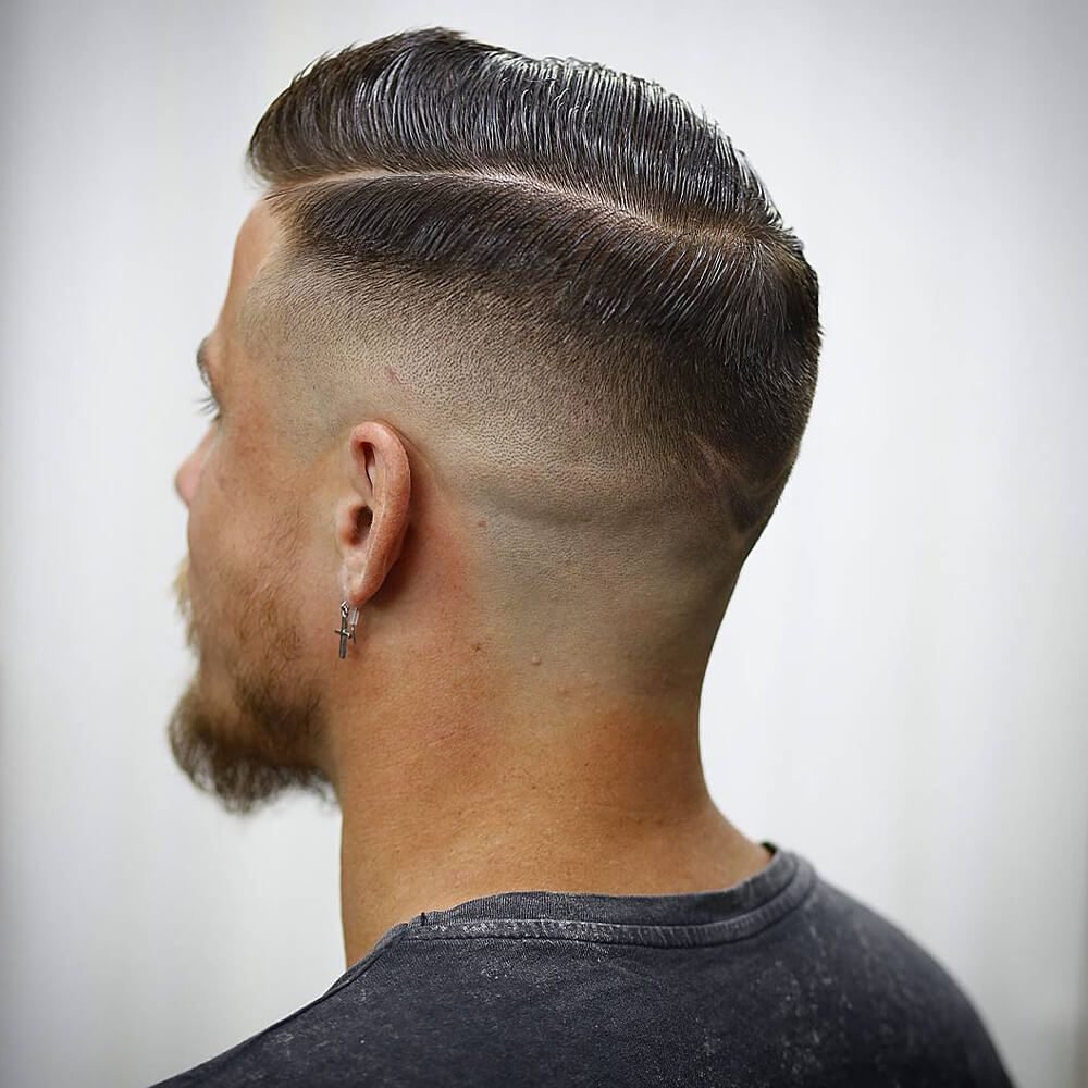 Corte americano com high fade subindo quase até o topo da cabeça, risca lateral marcada e topo penteado para o lado