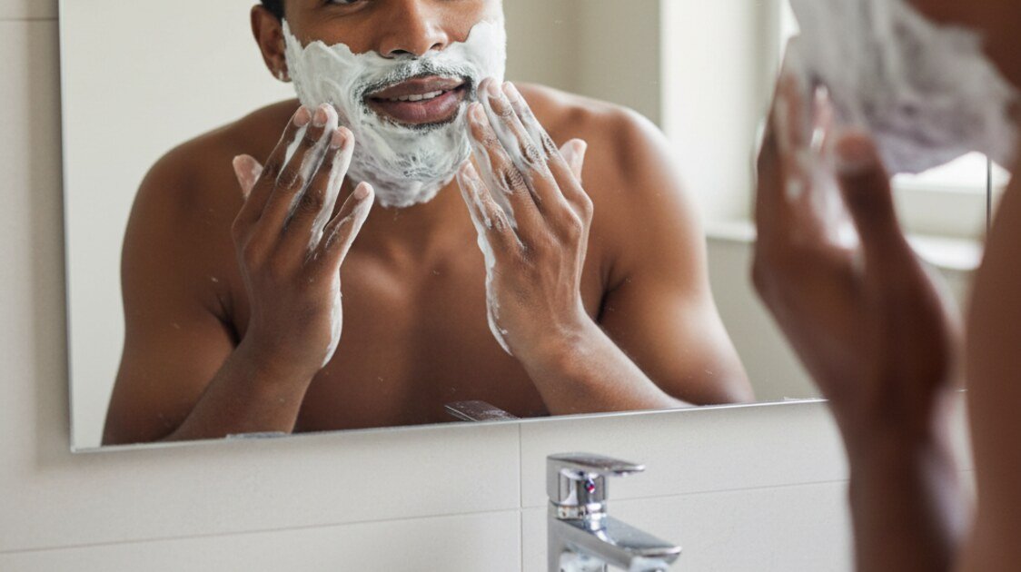 Homem preparando o rosto para fazer a barba com espuma
