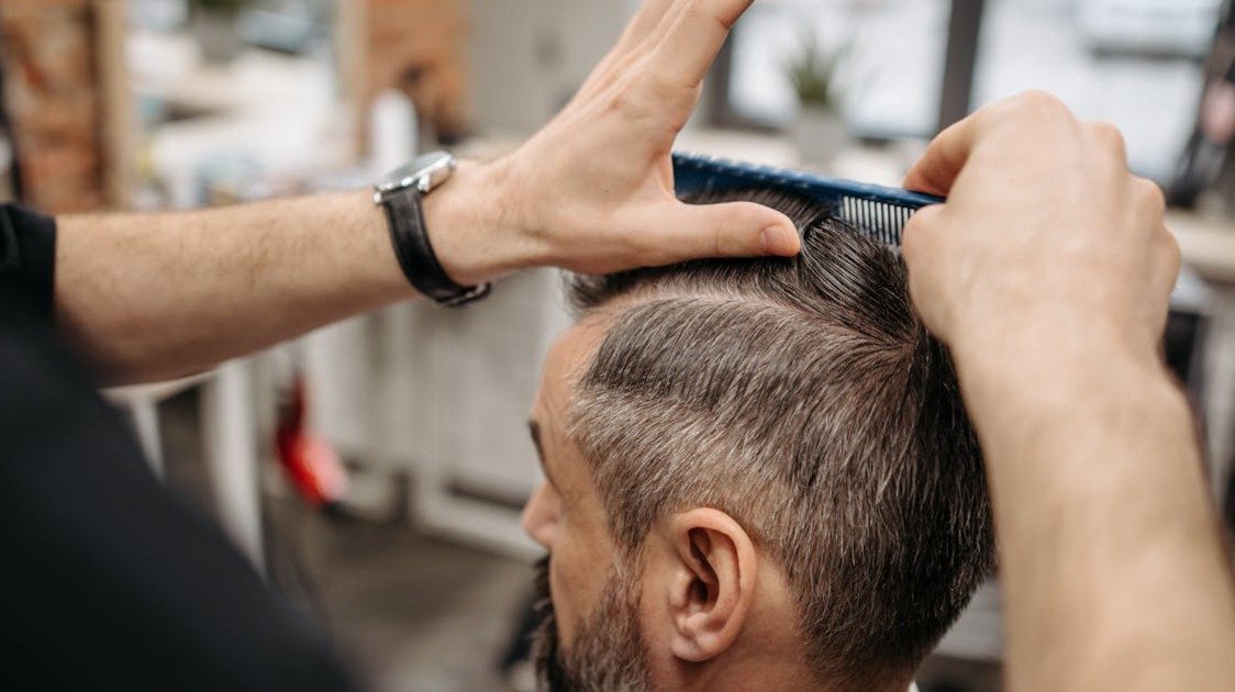 Close em corte side part masculino destacando a risca lateral e a textura do cabelo.