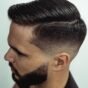 Homem com corte side part masculino bem definido em ambiente de barbearia premium.