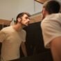 Homem de camiseta branca se olhando de perto no espelho do banheiro