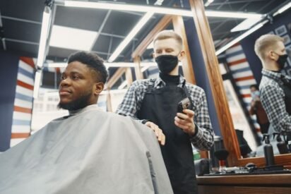 Barbeiro aparando a barba de um cliente com aparador elétrico