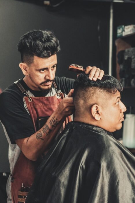 Barbeiro finalizando o corte de cabelo de um cliente na barbearia