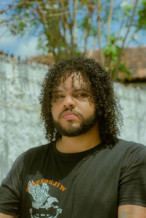 Homem com barba e cabelo cacheado médio, com volume natural e textura definida