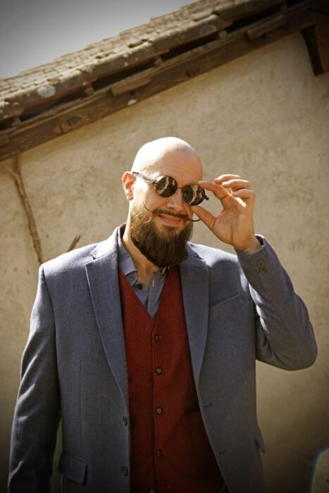 Homem careca de barba e óculos escuros sob a luz do sol