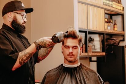 Barbeiro secando o cabelo de um cliente com secador para dar forma ao topo