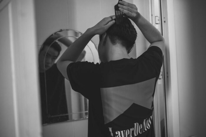 Homem penteando o cabelo em frente ao espelho do banheiro