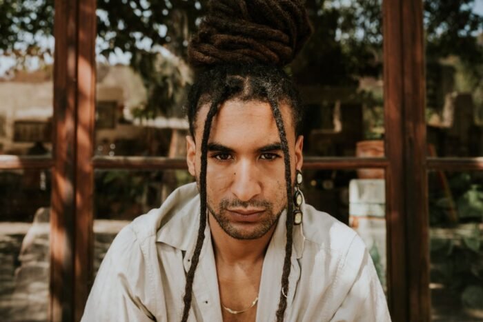 Homem com dreads presos em coque alto e algumas mechas soltas na frente