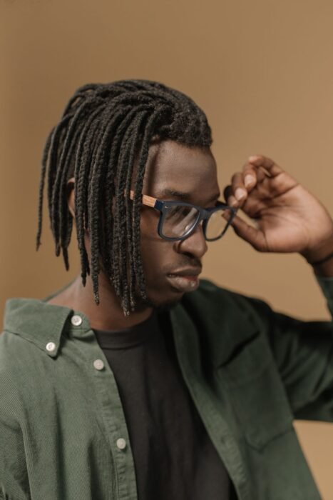 Homem de óculos com dreads finos de comprimento médio, soltos na altura do queixo