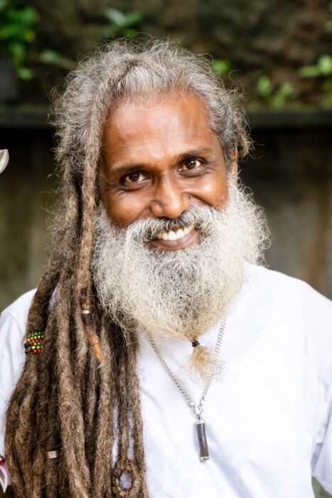 Homem mais velho com dreads longos e grisalhos e barba branca, sorrindo