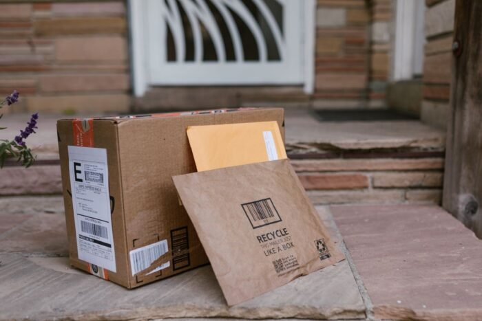 Caixa de papelão e envelope de encomenda deixados na porta de casa