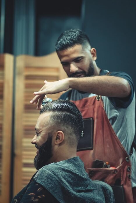 Barbeiro penteando e finalizando o cabelo de um cliente de barba