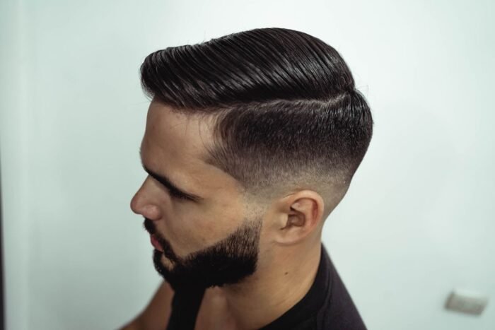 Perfil de homem com barba e laterais em degradê baixo, topo penteado para o lado