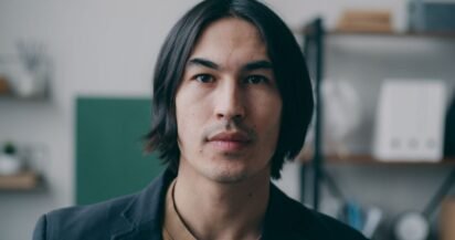 Homem com cabelo médio repartido ao meio, caindo para os dois lados do rosto