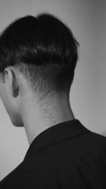 Nuca de um homem com cabelo curto e acabamento em degradê, vista de trás em preto e branco