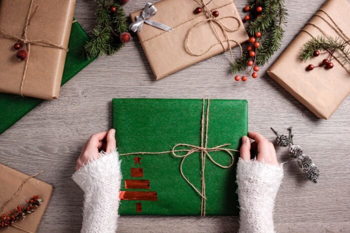 Presentes de Natal embrulhados em papel kraft e verde sobre mesa de madeira
