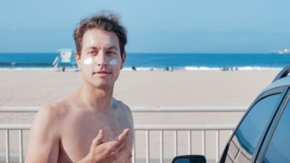 Homem na praia com protetor solar no rosto antes de pegar sol