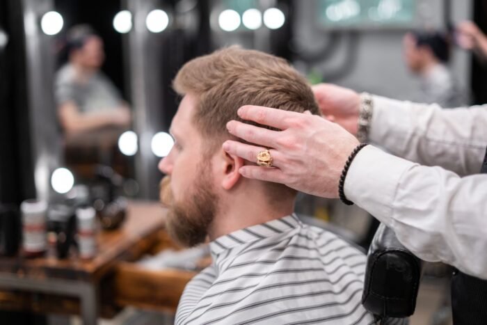 Barbeiro ajeitando o cabelo de um cliente de barba antes do corte