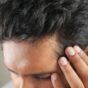 Homem passando a mão no couro cabeludo perto da linha do cabelo