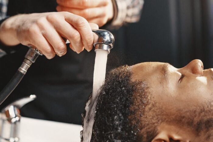 Homem tendo o cabelo lavado com água morna na pia do salão