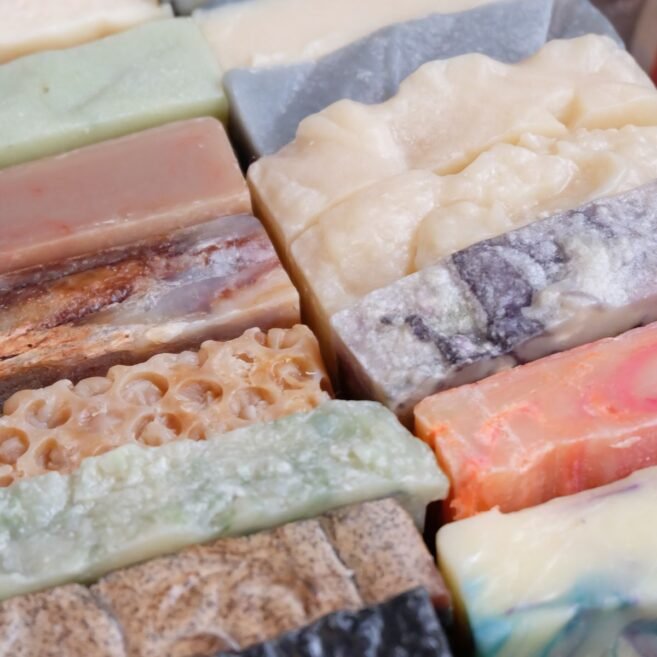 Sabonetes artesanais em barra de várias cores e texturas empilhados lado a lado