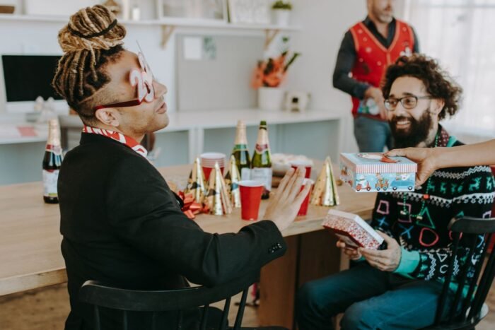 Homem de barba recebendo um presente embrulhado em festa de fim de ano do trabalho
